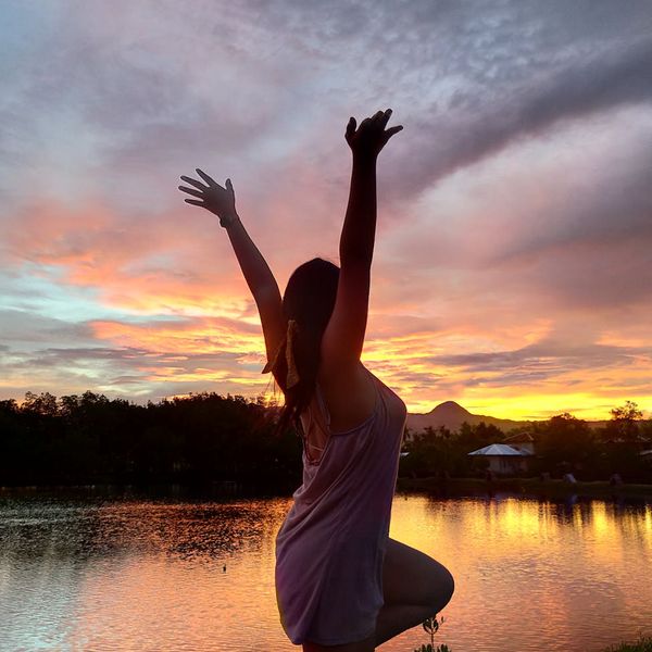 Silhouette of a person in a powerful warrior yoga pose against a glowing background.